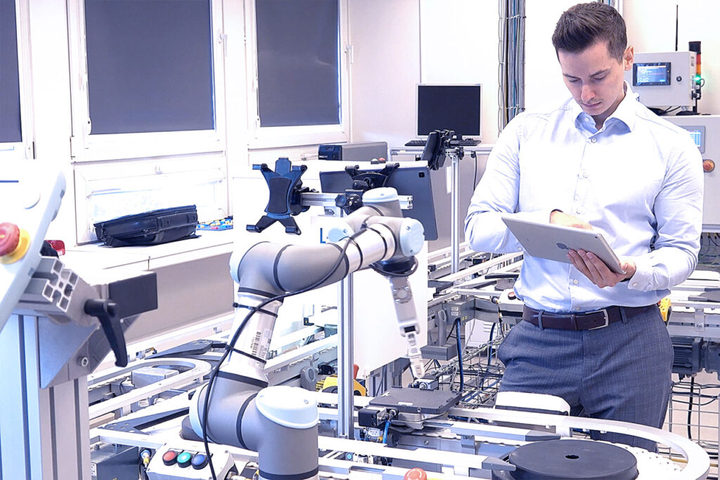 Specjalista korzystający z tabletu obok robota współpracującego na linii produkcyjnej